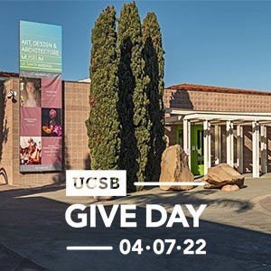 Front entrance of Art, Design & Architecture Museum, with trees and multi-color banner. In white, "UCSB Give Day 04-07-22" center bottom.