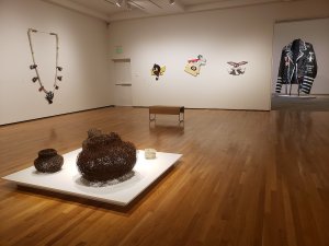Photo of "Ishi Glinsky: Upon a Jagged Maze" exhibition / sculpture, resin pieces on the wall, and large jacket on the right.